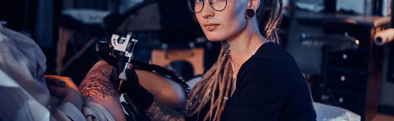 beautiful-creative-master-with-dreadlocks-is-working-new-peace-big-leg-tattoo-customer_613910-2929
