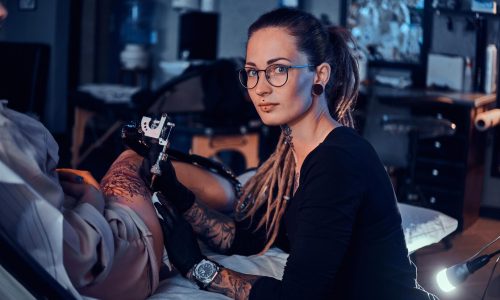 beautiful-creative-master-with-dreadlocks-is-working-new-peace-big-leg-tattoo-customer_613910-2929