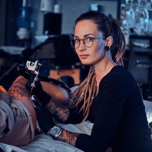 beautiful-creative-master-with-dreadlocks-is-working-new-peace-big-leg-tattoo-customer_613910-2929