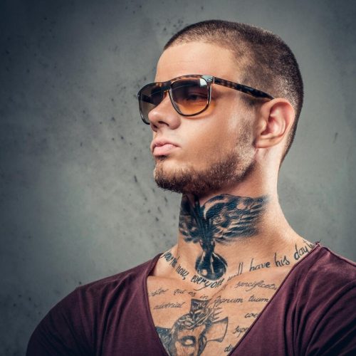 handsome-athletic-male-sunglasses-with-tattoos-his-arms-neck-posing-grey-artistic-background-studio_613910-15813