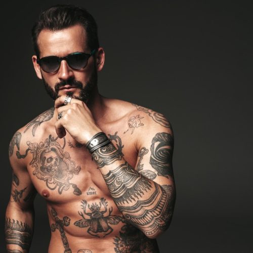 portrait-handsome-confident-stylish-hipster-lambersexual-model-sexy-modern-man-naked-torso-with-tattoosfashion-male-posing-studio-dark-background-sunglasses_158538-21689-2