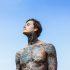 tattooed-man-with-headphones-against-blue-sky-ocean_1321-846