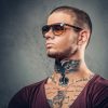 handsome-athletic-male-sunglasses-with-tattoos-his-arms-neck-posing-grey-artistic-background-studio_613910-15813